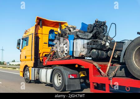 POV schweren Flurförderzeug Sattelauflieger Flachbett Plattform Transport zerstörte Bergungs LKW-Chassis und Kabine Maschine auf der gemeinsamen Autobahn Straße bei hell Stockfoto