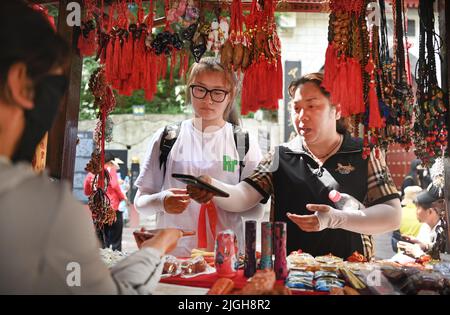 (220711) -- XI'AN, 11. Juli 2022 (Xinhua) -- Touristen kaufen Souvenirs an der malerischen Stelle des Berges Huashan in der nordwestlichen chinesischen Provinz Shaanxi, 10. Juli 2022. Der Berg Huashan ist einer der fünf berühmtesten malerischen Berge Chinas und bekannt für seine steilen und gefährlichen Gipfel. Die Management-Verwaltung des malerischen Gebietes Mount Huashan wird ihre Politik des freien Eintritts in diesem Monat fortsetzen, um mehr Besucher anzuziehen. (Xinhua/Tao Ming) Stockfoto