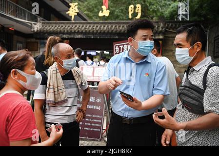 (220711) -- XI'AN, 11. Juli 2022 (Xinhua) -- Ein Mitarbeiter (2. R) hilft Besuchern am Eingang des malerischen Ortes Mount Huashan in der nordwestlichen chinesischen Provinz Shaanxi, 9. Juli 2022. Der Berg Huashan ist einer der fünf berühmtesten malerischen Berge Chinas und bekannt für seine steilen und gefährlichen Gipfel. Die Management-Verwaltung des malerischen Gebietes Mount Huashan wird ihre Politik des freien Eintritts in diesem Monat fortsetzen, um mehr Besucher anzuziehen. (Xinhua/Tao Ming) Stockfoto