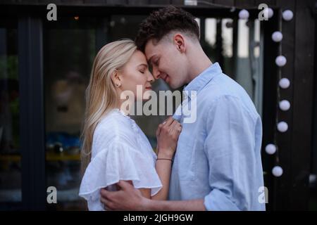 Junges Paar in der Liebe Kuscheln und Küssen im Freien auf der Terrasse, Wochenende in winzigen Haus auf dem Land, nachhaltiges Leben. Stockfoto