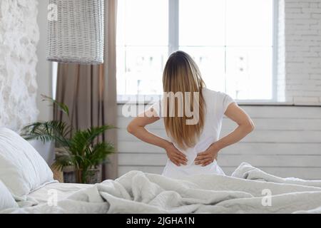 Nicht erkennbare Frau, die zu Hause im Schlafzimmer unter Rückenschmerzen leidet Stockfoto