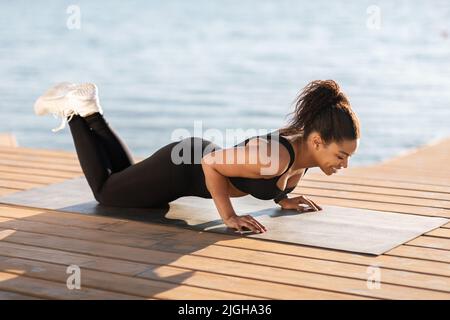 Schwarze Frau macht Yoga am Strand Stockfoto