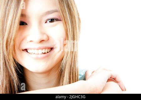 Blasse Schönheit, natürliches Lächeln. High-Key-Bildserie des gleichen Modells. Augenkontakt und ein natürliches Lächeln auf dem Gesicht eines schönen weiblichen asiatischen Modells. Stockfoto