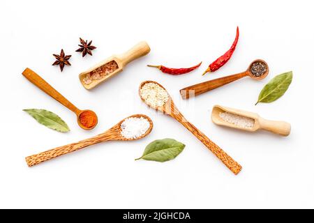 Vielfalt an bunten Gewürzen und Kräutern in Holzlöffeln auf Küchentisch, Draufsicht Stockfoto