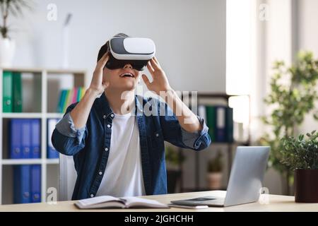 Freizeit Im Büro. Porträt eines aufgeregt jungen Mannes mit VR-Brille am Arbeitsplatz Stockfoto