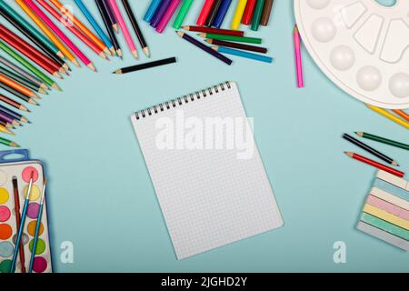 Leeres Blatt Papier mit Mathematik-Notizbuch, Kunstschulbedarf für Malerei, auf blauem Hintergrund mit Platz für Text. Bunte Stifte, Marker Stockfoto