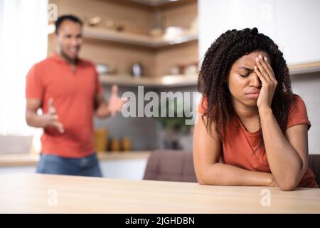 Wütender, tausendjähriger afroamerikanischer Ehemann, der verärgert beleidigte Ehefrau im Kücheninnenraum anschrie, verschwommen Stockfoto