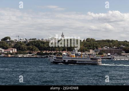 Blick auf die Fähre, die vor dem Topkapi-Palast in Istanbul vorbeifährt. Es ist ein sonniger Sommertag. Stockfoto