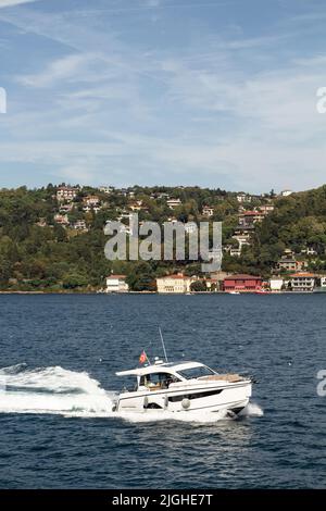 Blick auf eine Yacht, die auf dem Bosporus und der asiatischen Seite Istanbuls vorbeifährt. Es ist ein sonniger Sommertag. Wunderschöne Reiseszene. Stockfoto