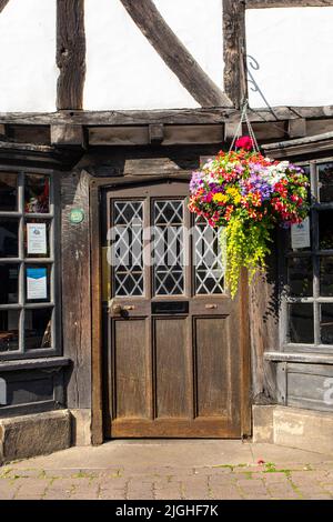 Ein hängender Korb und eine alte Eingangstür in den alten Straßen der Stadt York an einem Sommertag Stockfoto