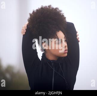 Vorbereitung auf einen Lauf. Eine attraktive junge Sportlerin, die an einem nebligen Morgen draußen steht. Stockfoto
