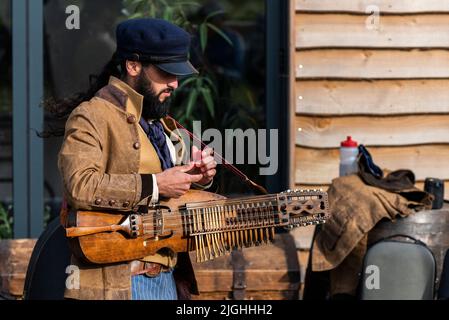 Ein Musiker aus der alten Zeit Matrosen Tuning einer Nyckelharpa am Newquay Orchard Amphitheater in Cornwall. Stockfoto