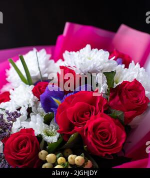 Nahaufnahme eines bunten Blumenarrangements aus verschiedenen Blumen. Original schöner heller Strauß mit roten Rosen, weißer Chrysantheme Stockfoto