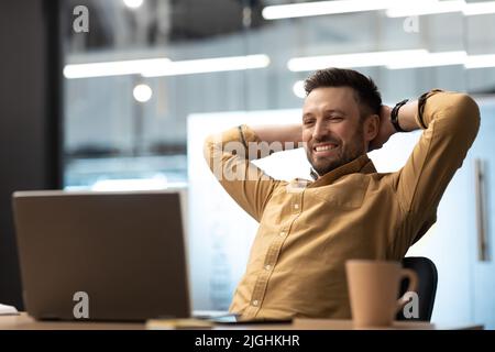 Geschäftsmann, Der Entspannt Auf Einem Stuhl Sitzt Und Den Laptop Im Büro Betrachtet Stockfoto