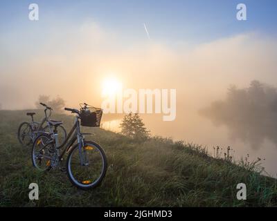 Sonnenuntergang über der Wiese neben Bug und Fahrrad. Podlasie. Podlachia. Polen, Europa. Die Region heißt Podlasko oder Podlasze. Stockfoto