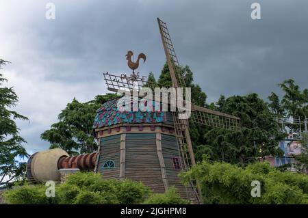 Windmühle umgeben von Bäumen Disneyland Paris mit bewölktem Himmel Hintergrund Stockfoto