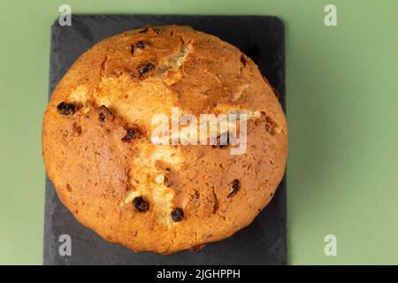 Klassischer Quark-Kuchen mit Rosinen. Auf einem Cupcake auf einem schwarzen Schneidebrett. Stockfoto