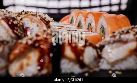 Nahaufnahme einer Rolle Philadelphia mit Frischkäse, Lachs, Gurke und Kaviar liegt unter den anderen Rollen. Selektiver Fokus. Verschwommenes Fron Stockfoto