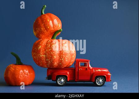 Retro-LKW mit Kürbissen und Blättern auf blauem Hintergrund. Konzept von Thanksgiving Tag, Halloween und Herbst Postkarten. Stockfoto