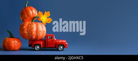 Retro-LKW mit Kürbissen und Blättern auf blauem Hintergrund. Konzept von Thanksgiving Tag, Halloween und Herbst Postkarten. Stockfoto