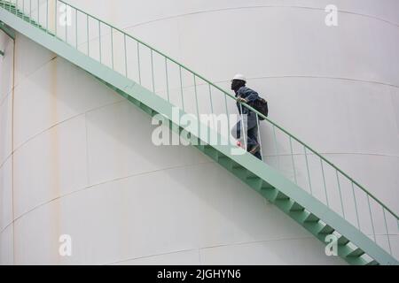 Mann, der die Treppenaufgänge überprüft, Sichtlagerbehälter, Chemikalie. Stockfoto