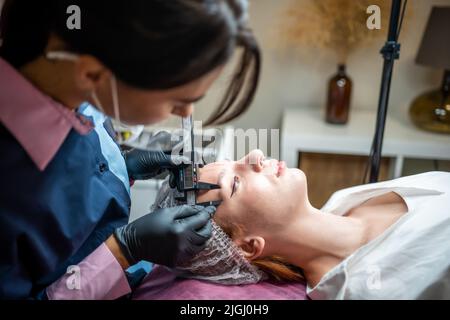 Beauty Master Messen Augenbrauen mit Zirkel vor permanentem Make-up. Stockfoto