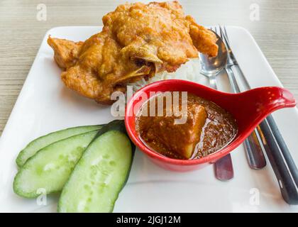 Nahaufnahme des Schweinekoteletts mit currigem Reis und Gurke. Stockfoto