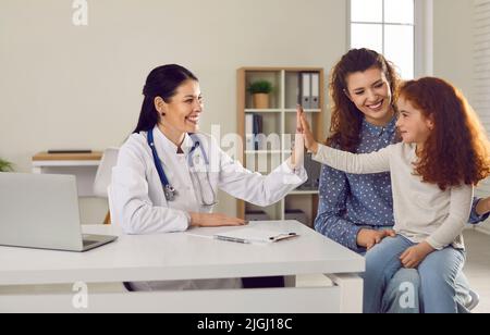 Die Kinderärztin gibt fünf Mädchen, die sich einer medizinischen Untersuchung mit ihrer Mutter unterzogen Stockfoto