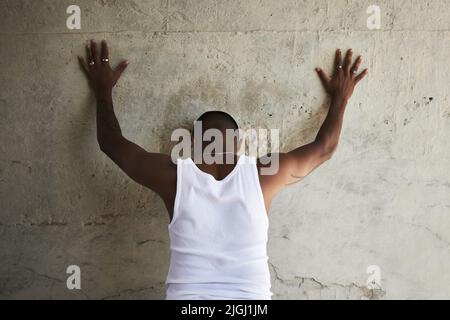 Hände hoch und spreizen sie. Rückansicht eines Mannes, der sich mit den Händen nach oben an einer Stadtmauer lehnt. Stockfoto