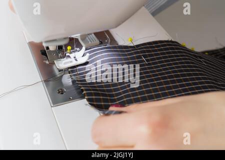 Näherin Frau arbeitet an Nähmaschine. Schneiderhände arbeiten in der Nähfabrik Stockfoto