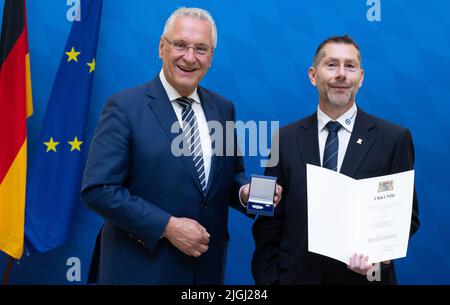 11. Juli 2022, Bayern, MŸnchen: Joachim Herrmann (l, CSU), Bayerischer Innenminister, verleiht Andreas Dietz, ehemaliges Mitglied der Wasserwacht Bayern, die Bayerische Staatsmedaille "Stern der Sicherheit". Mit der Bayerischen Staatsmedaille "Stern der Sicherheit" würdigt der Bayerische Innenminister seit 2013 herausragende Verdienste um die innere Sicherheit. Foto: Sven Hoppe/dpa Stockfoto