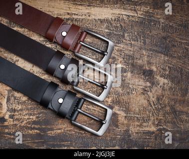 Männer-Leder-Hosengürtel im Hintergrund aus gealtertem Holz. Herren Mode Accessoires Schrank. Echtes Leder, handgefertigt Stockfoto