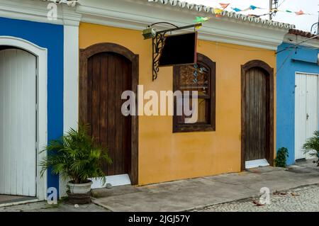 Schöne Fassade.dekoriert mit einer Topfpflanze. Altes Haus in Orange mit braunen Holztüren und -Fenstern. Stadt Porto Seguro. Bahia. Brasilien. Stockfoto