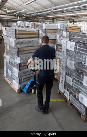 Ludwigsburg, Deutschland. 11.. Juli 2022. Ein Mitarbeiter der Feuerwehr schiebt eine Palette mit Notfallbetten in ein Lager für Notfälle des Bevölkerungsschutzes des Landkreises Ludwigsburg. Damit können im Falle eines Gasnotfalls mögliche Heizhallen ausgestattet werden. Quelle: Bernd Weißbrod/dpa/Alamy Live News Stockfoto