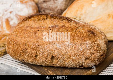 Hausgemachtes natürliches Brot. Verschiedene Arten von frischem Brot als Hintergrund, perspektivische Ansicht mit Kopierraum. Stockfoto