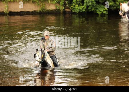 Ein Teenager, der auf seinem Pferd durch den Fluss Eden, Appleby Horse Fair und Appleby in Westmorland, Cumbria, reitet Stockfoto