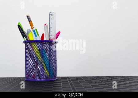 Mehrere Schulmaterialien in einem Stifthalter auf dem Schreibtisch auf weißem Hintergrund isoliert organisiert mit leerem Platz für Text auf der rechten Seite Stockfoto