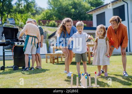 Mehrere Generationen Familienspiel Werfen Sie ein Ringspiel, wenn Sie im Sommer auf der Gartenparty draußen auf dem Hinterhof im Freien feiern. Stockfoto