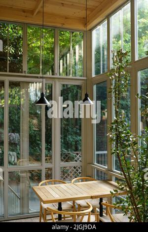 Gemütliches Interieur des Restaurants mit Design Holztisch große Fenster Lampen, Pflanzen in Öko-natürlichen Stil Stockfoto