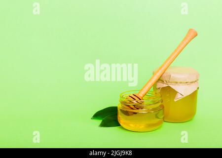 Honig im Glas mit Blättern und Honigtaube auf farbigem Hintergrund Draufsicht mit Text kopieren. Stockfoto