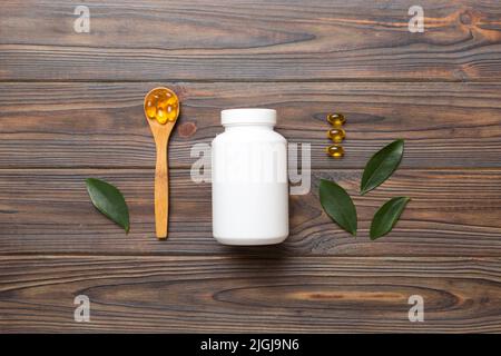 Omega-3 Kapseln liegen in einer weißen Flasche auf einem Tisch mit grünem Blatthintergrund. Fischöltabletten. Biologisch aktive Zusatzstoffe. omega 6, Omega 9, Vitam Stockfoto