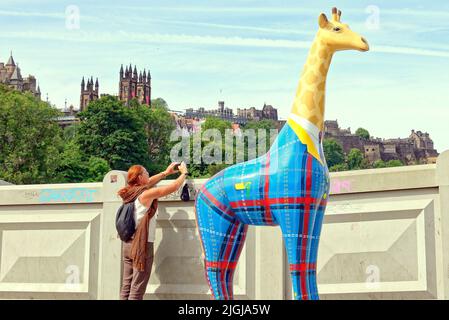 Edinburgh, Schottland, Großbritannien Juli 11. 2022. Wetter in Großbritannien: Sonnig, da Einheimische und Touristen in die Princes Street Gardens und die lokalen Straßen gingen, um die Sonne zu genießen, während eine Reihe von kunstinspirierten Giraffenstatuen auf den Gehwegen gefunden werden..Edinburgh Zoo, in Zusammenarbeit mit kreativen Produzenten Wild in Art, Präsentieren Sie Giraffe About Town – unsere große öffentliche Kunstveranstaltung in Edinburgh in diesem Sommer. Credit Gerard Ferry/Alamy Live News Stockfoto