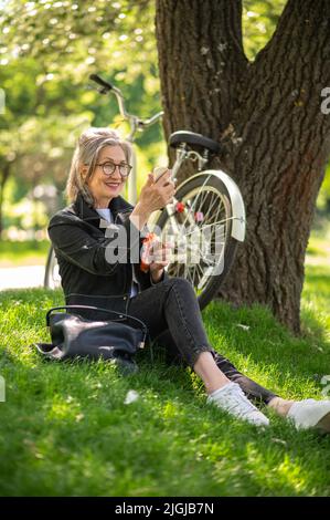 Eine reife Frau in einer Brille schminke sich Stockfoto