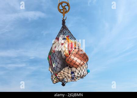 Hängendes Netz mit Plastikmüllflaschen, Dosen und Behältern vor einem blauen Himmel mit Kopierfläche Stockfoto