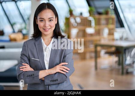 Junge selbstbewusste asiatische Geschäftsfrau im Büro stehend, Porträt. Stockfoto