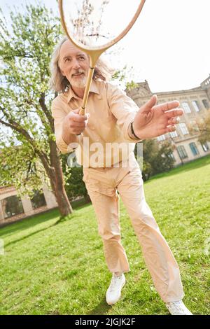Hübscher männlicher Mensch, der einen fliegenden Federball anschaut Stockfoto
