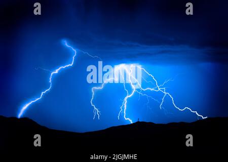 Helle Blitze auf Berg mit Funkturm für Leistung und Kommunikation Silhouette Stockfoto