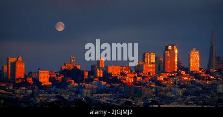 Goldenes Sonnenuntergangslicht, das auf die Skyline der Wolkenkratzer des San Francisco City Building leuchtet und Vollmond aufgeht Stockfoto