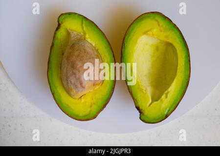 Zwei frisch gepflückte, reife Avocado-Scheiben aus biologischem Superfood auf weißem Schneidebrett. Selektiver Fokus. Stockfoto
