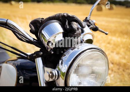 Nahaufnahme Vorderansicht eines Motorrads, das in der Sonne auf einem Feldweg geparkt ist Stockfoto